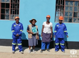 建設完了間近の職員棟の前で笑顔を見せる女性の建設作業員のADRAスタッフ